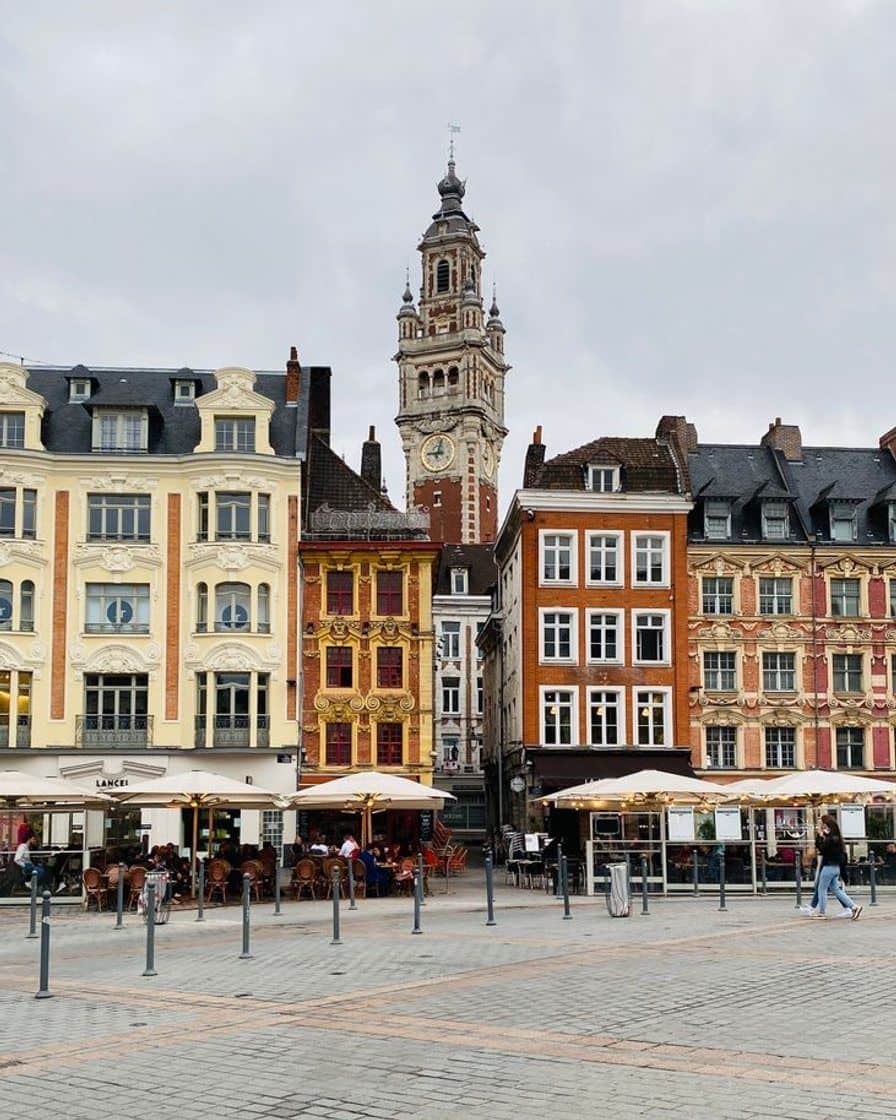 Red-brick belfry of Lille town hall under a clear Sunday sky, visitors at the foot of the tower