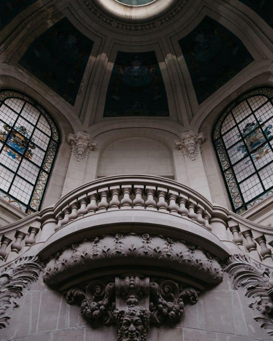 Bright atrium of the Palais des Beaux-Arts in Lille, tall glass windows, sculptures on plinths and visitors on the pale floor