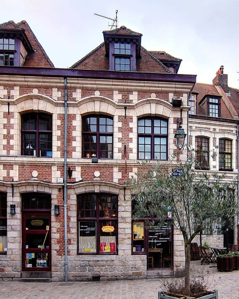Small cobbled Place aux Oignons in Vieux-Lille, low brick houses with painted shutters and a café terrace on a weekday morning